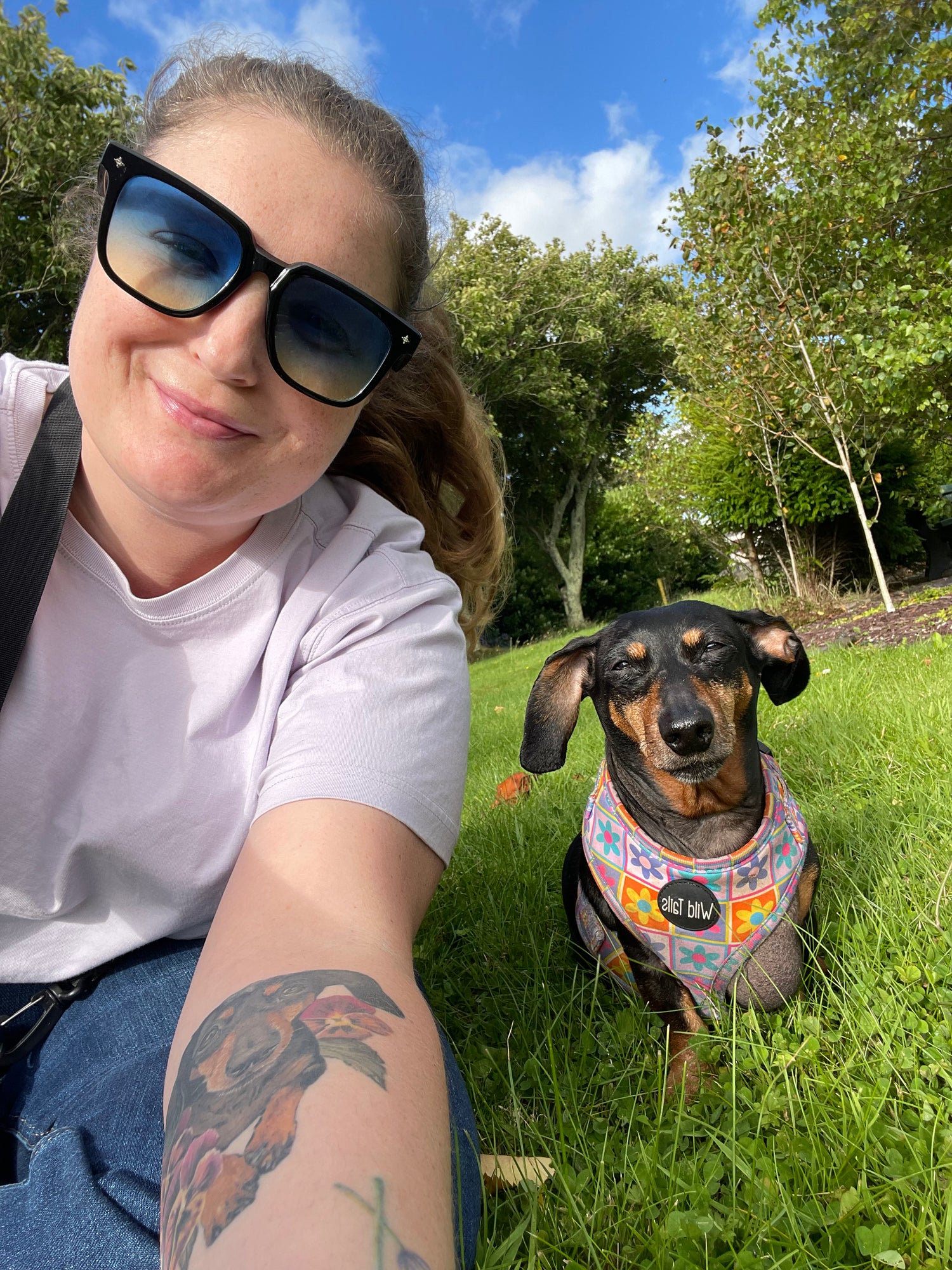 Shannon Karpinski, founder of Alchemilla Herbcraft, smiling with her dachshund in a sunny field—honoring the joy of simple, grounded connection to nature.
