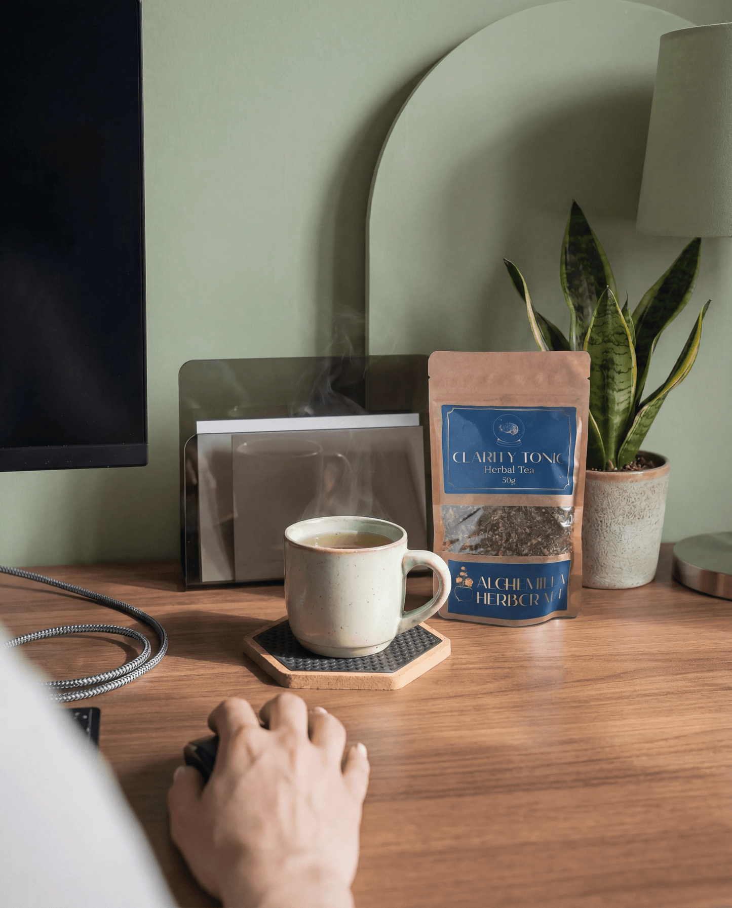 A cup of clarity tonic herbal tea next to a laptop and journal, styled as a mindful productivity ritual for focus.