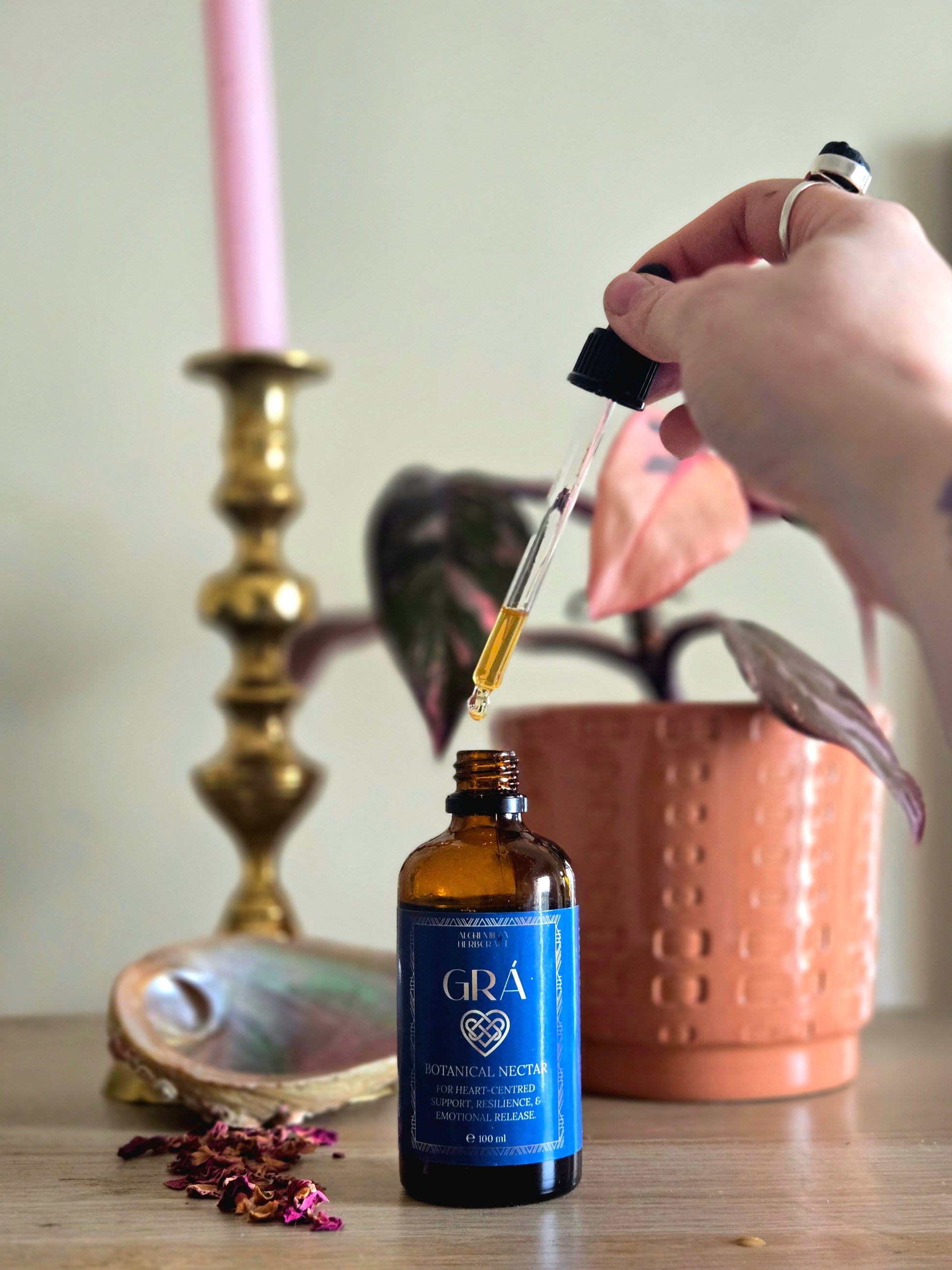 Bottle of Grá herbal tincture with a dropper on a wooden surface.