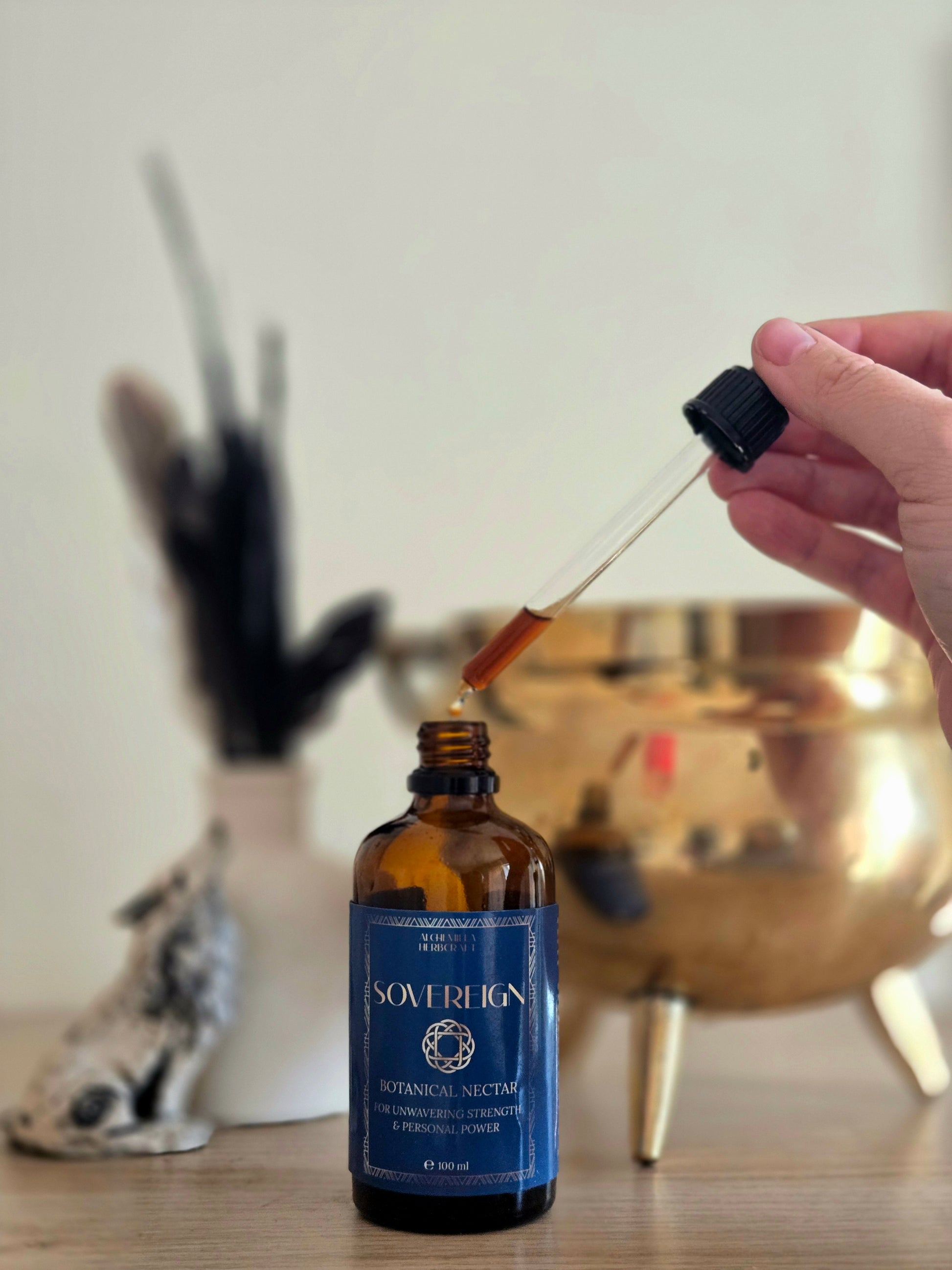 Hand using a dropper from a bottle labeled 'Sovereign' on a wooden surface.